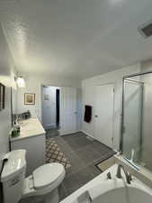 Full bath with a textured ceiling, double vanity, and tile patterned flooring