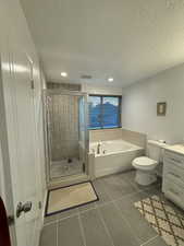 Full bathroom featuring a garden tub, tile patterned floors, a textured ceiling, a shower stall, and vanity