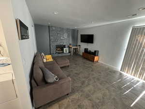 Living room featuring washer / clothes dryer, a stone fireplace, and recessed lighting