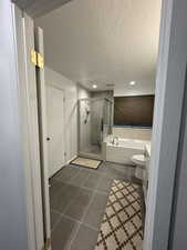 Full bath featuring tile patterned flooring, a bath, a stall shower, a textured ceiling, and vanity