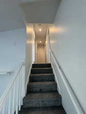 Stairs with carpet floors and recessed lighting