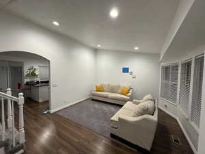 Living area with a textured ceiling, recessed lighting, arched walkways, and wood finished floors