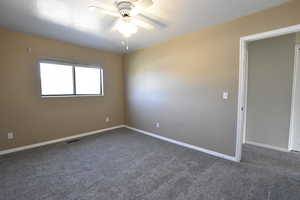 Carpeted empty room with a ceiling fan and baseboards