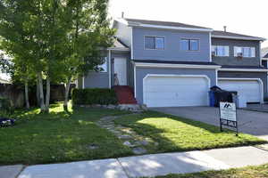 View of front facade featuring a front yard, an attached garage, driveway, entry steps, and roof with shingles