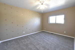 Carpeted spare room featuring a ceiling fan and baseboards