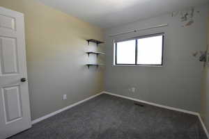 Spare room with dark carpet and baseboards