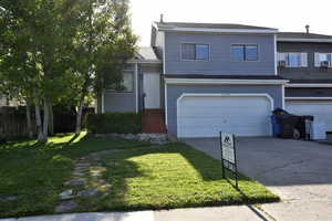 View of front facade featuring driveway, a front lawn, an attached garage, and roof with shingles