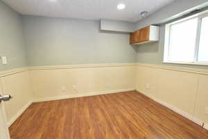 Unfurnished room with plenty of natural light, wood finished floors, wainscoting, and recessed lighting