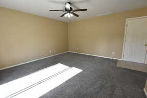 Carpeted spare room with a ceiling fan and baseboards