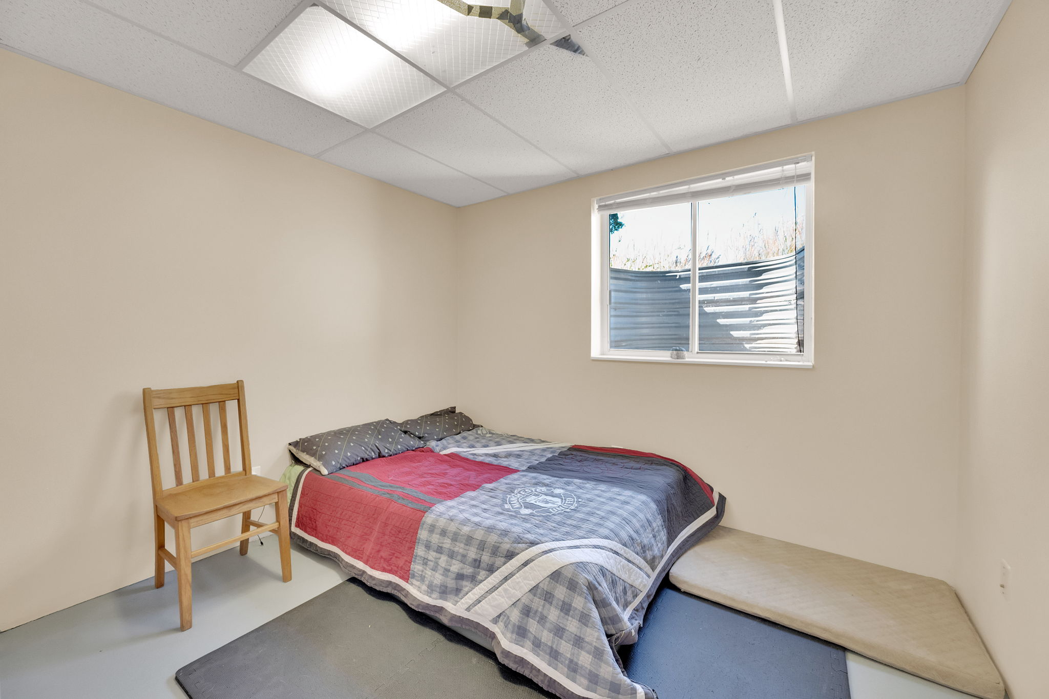 Bedroom featuring a paneled ceiling and finished concrete flooring