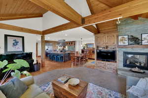 Living area featuring high vaulted ceiling, light wood-style floors, a fireplace, a wooden ceiling with exposed beams, and recessed lighting