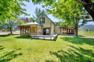 Back of property featuring a yard, stone siding, a metal roof, and french doors