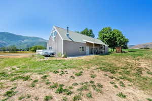View of property exterior with an outdoor structure, a mountain view, a pole building, and a metal roof