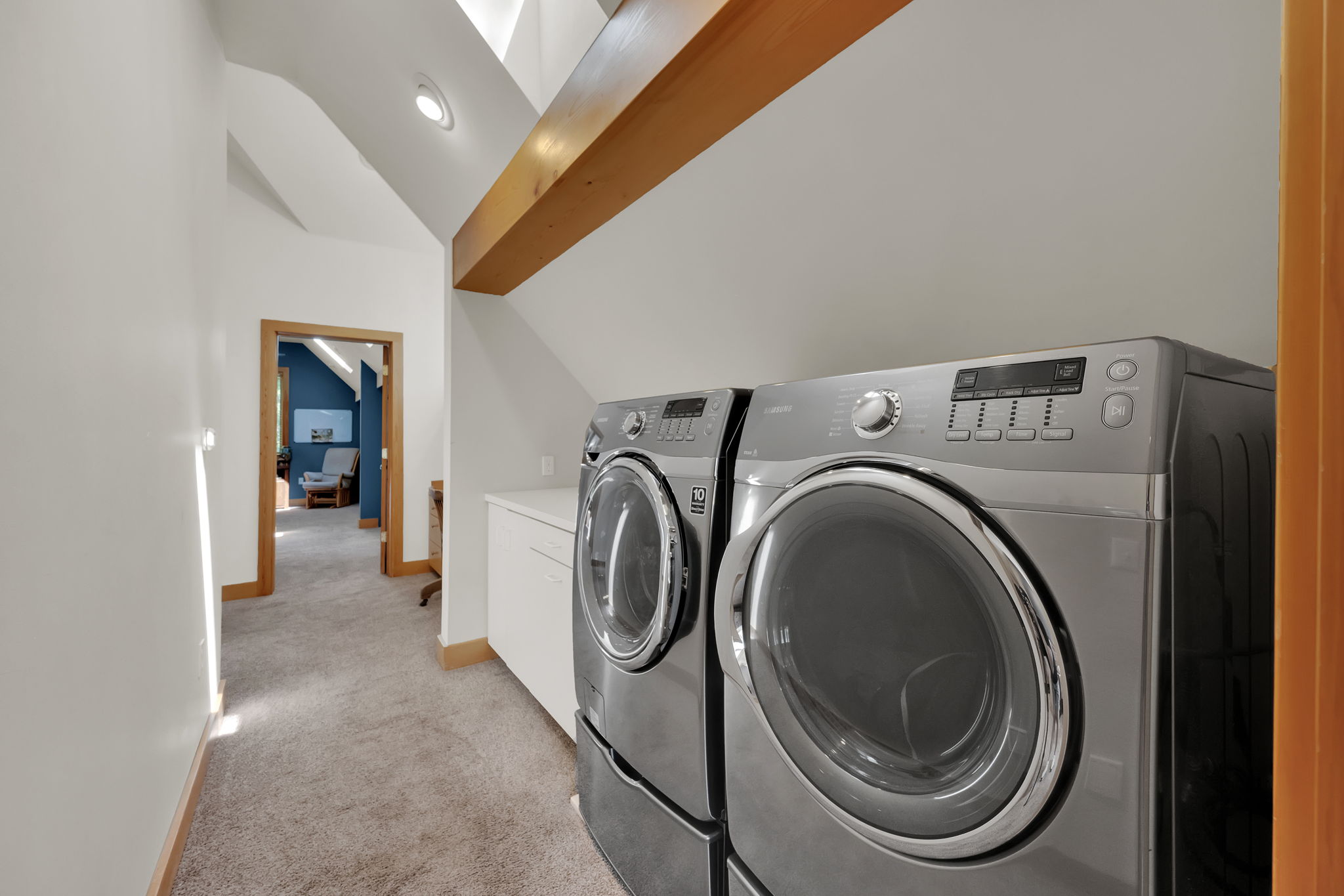 Laundry area with independent washer and dryer, light carpet, and cabinet space