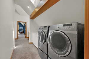 Laundry area with independent washer and dryer, light carpet, and cabinet space