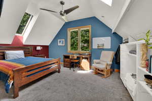 Bedroom with a skylight, carpet flooring, lofted ceiling, an office area, and ceiling fan