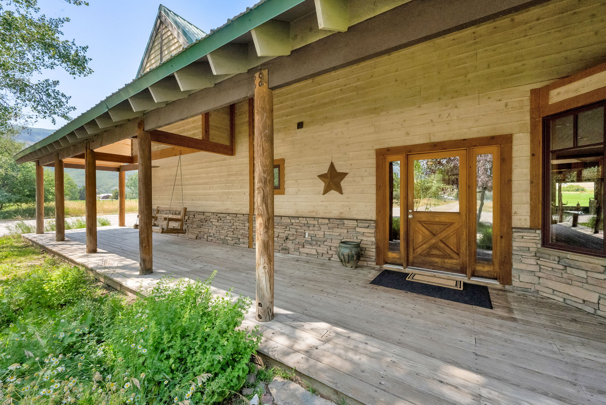 Property entrance with stone siding, a wooden deck, and a metal roof
