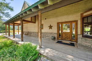 Property entrance with stone siding, a wooden deck, and a metal roof