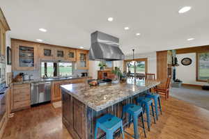 Kitchen featuring recessed lighting, a center island, a breakfast bar area, island range hood, and light wood-style flooring