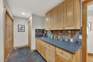 Kitchen featuring light brown cabinets, dark countertops, backsplash, and recessed lighting