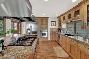 Kitchen featuring island range hood, stainless steel appliances, recessed lighting, light stone counters, and light wood-style flooring