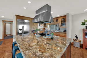 Kitchen featuring island range hood, stainless steel built in fridge, recessed lighting, light wood-style floors, and a large island