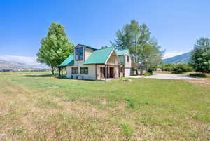 Chalet / cabin featuring driveway, a front yard, a metal roof, and a mountain view
