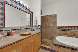 Full bath with vanity, tiled shower, tile walls, a garden tub, and a wainscoted wall