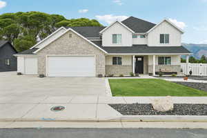 View of front of house featuring concrete driveway, stone siding, an attached garage, covered porch, and board and batten siding