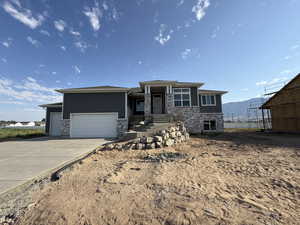 Prairie-style house featuring driveway, stone siding, an attached garage, and a mountain view