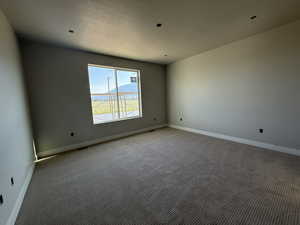 Empty room featuring light colored carpet and baseboards