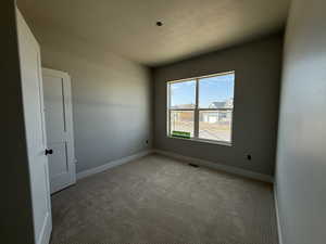 Empty room featuring light carpet and a textured ceiling