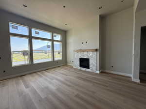 Unfurnished living room with light wood-style floors, a stone fireplace, and recessed lighting