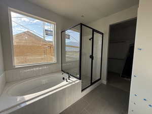 Bathroom featuring a bath, a stall shower, tile patterned floors, and a walk in closet