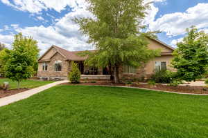View of front of home featuring stone siding, a front yard, and stucco siding