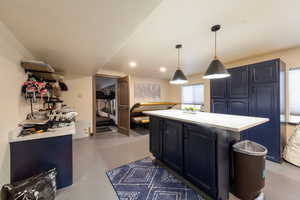 Kitchen with a kitchen island, blue cabinetry, light countertops, concrete floors, and recessed lighting