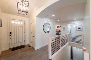 Entryway with wood finished floors, recessed lighting, arched walkways, and a chandelier