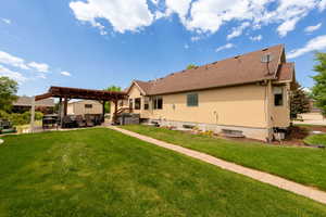 Rear view of property featuring a jacuzzi, a pergola, a patio area, a yard, and outdoor lounge area