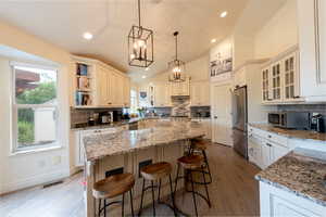 Kitchen featuring a kitchen island, vaulted ceiling, a breakfast bar, decorative backsplash, and plenty of natural light