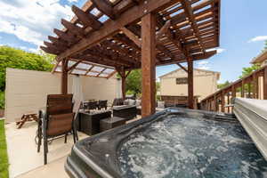 View of patio with a pergola, an outdoor hangout area, and a hot tub