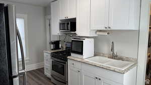 Kitchen with appliances with stainless steel finishes, white cabinetry, dark wood-style floors, and washer / clothes dryer