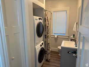 Laundry room with stacked washer / drying machine and dark wood finished floors