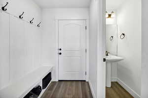 Mudroom featuring dark wood-type flooring and baseboards