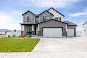 Craftsman-style home featuring a porch, concrete driveway, an attached garage, stone siding, and a mountain view