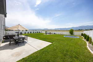 Fenced backyard with a mountain view, a patio, and outdoor dining area