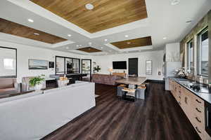 Clubhouse - Living room with dark wood-style floors, wood ceiling, recessed lighting, and a tray ceiling