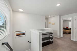Hall featuring an upstairs landing, healthy amount of natural light, carpet flooring, and recessed lighting