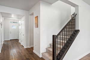 Entrance foyer with stairway, dark wood finished floors, and a chandelier