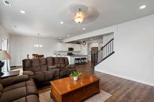 Living area with a chandelier, stairway, dark wood-style floors, ceiling fan, and a textured ceiling