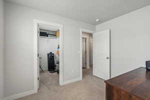 Carpeted bedroom with a desk and a walk in closet